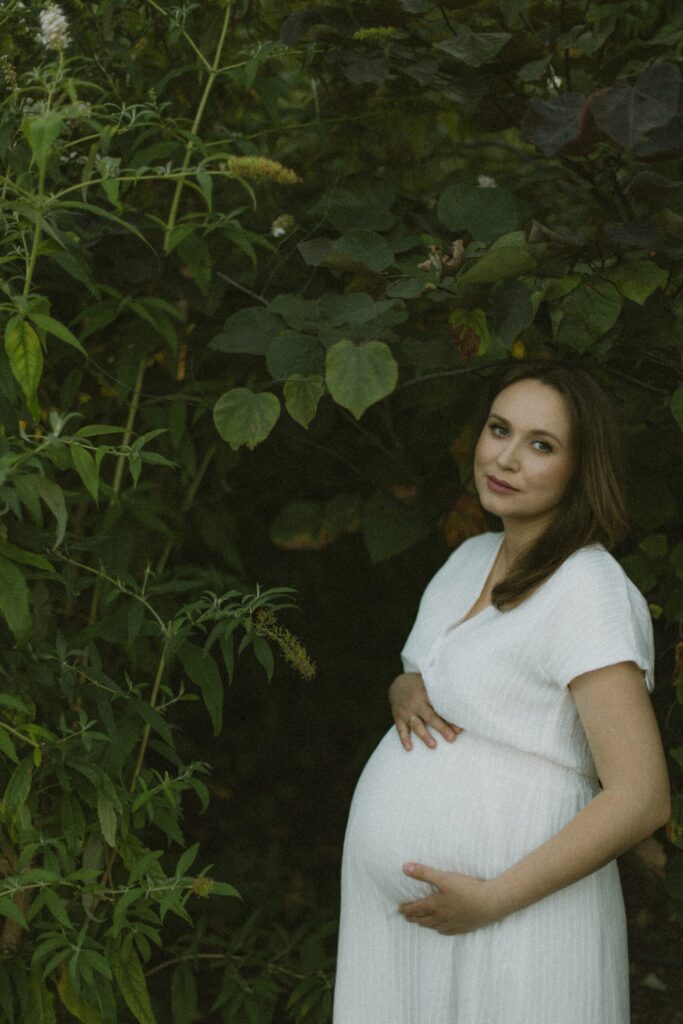sesja fotograficzna ciążowa w plenerze na tle zielonej roślinności, zdjęcia na pamiątkę